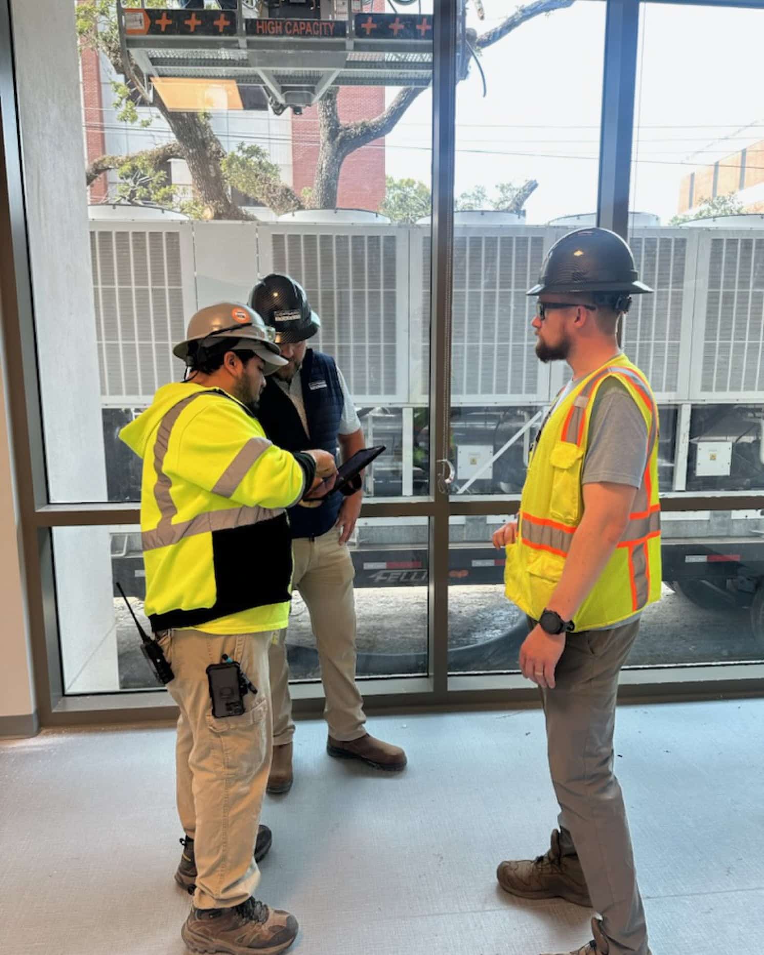 three lightgauge co workers huddled up looking at an ipad while on a construction site